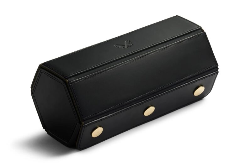 A hexagonal black leather case with gold buttons on one side and a subtle embossed logo on the top—perfect for anyone seeking luxury accessories and a style upgrade.