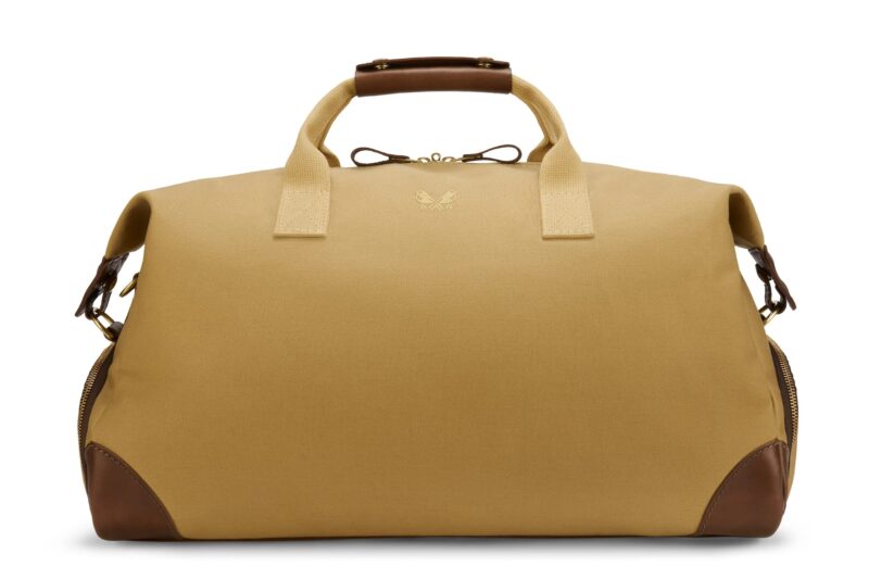 Tan duffle bag with brown leather accents on the handles and corners, featuring a small logo on the front and zipper closures on the sides—perfect for those seeking luxury accessories to upgrade your style.
