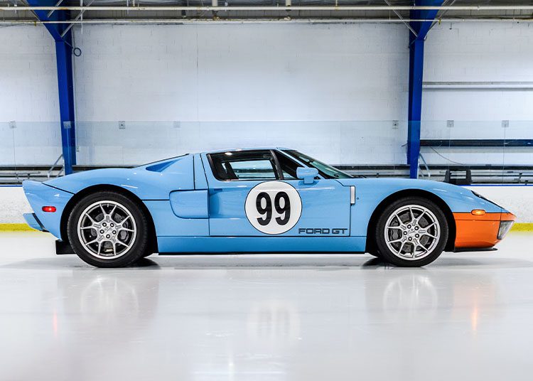 A stunning blue Ford GT Heritage Edition, proudly marked with the number 99, reminiscent of Wayne Gretzky's iconic legacy, is parked indoors on a smooth, reflective floor.