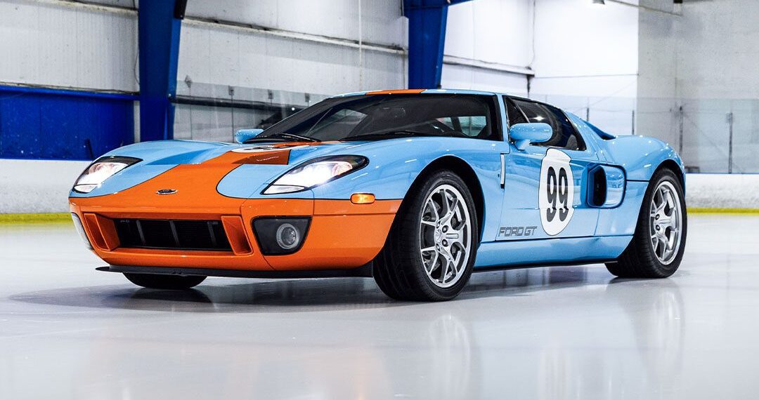 A stunning Ford GT Heritage Edition, boasting a blue and orange paint job with the iconic number 98—an homage to Wayne Gretzky—is parked indoors on a polished surface. Now available for sale, this beauty is ready to turn heads wherever it goes.