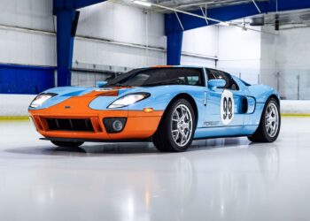 A stunning Ford GT Heritage Edition, boasting a blue and orange paint job with the iconic number 98—an homage to Wayne Gretzky—is parked indoors on a polished surface. Now available for sale, this beauty is ready to turn heads wherever it goes.