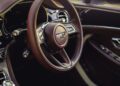Close-up of a luxury car interior featuring a brown Heritage Leather Interior, Bentley steering wheel, dashboard, and door controls.