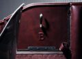 Close-up of a Bentley’s Heritage Leather Interior in burgundy, featuring a metal handle and an embossed letter “B” on the door panel.