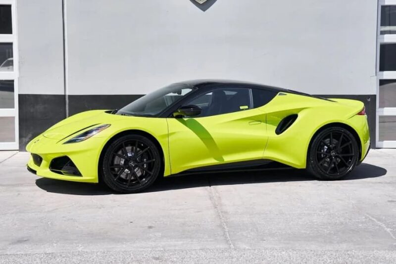 A bright yellow luxury car with black rims is parked in front of a white wall and garage doors.