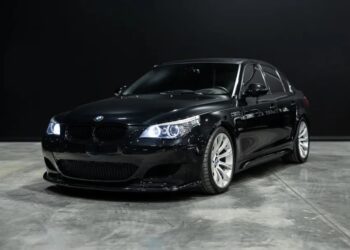 A black BMW sedan with illuminated headlights, parked on a concrete floor against a dark background—an eye-catching choice for those seeking manual transmission cars.