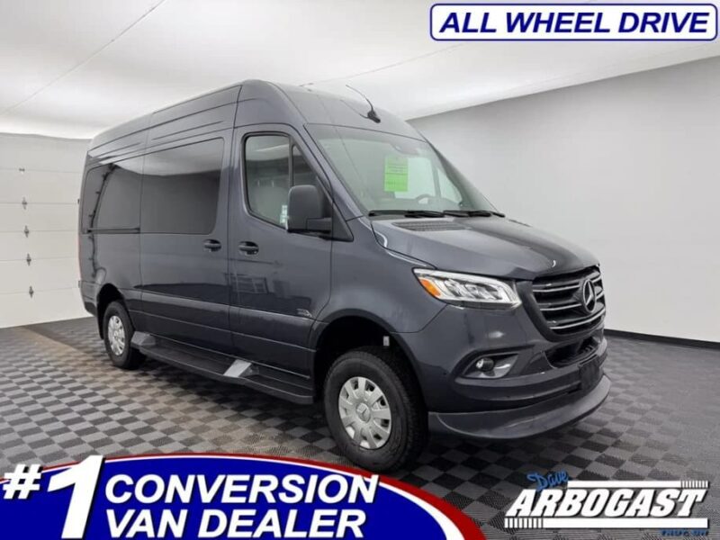 A dark gray luxury van is parked in a showroom with text overlay indicating it is an all-wheel drive at a top conversion van dealer, Dave Arbogast. Perfect choice if you’re seeking a distinctive luxury car for sale.