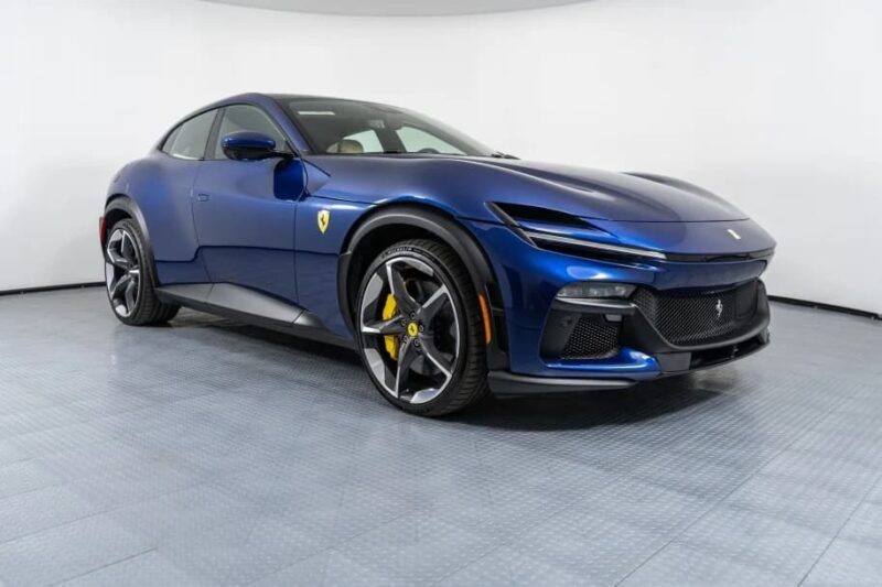 A blue Ferrari Purosangue SUV is parked in a well-lit showroom with a clean, white background and tiled floor, offering an elegant glimpse of the Ferrari Purosangue for sale.