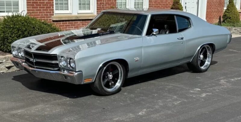 The classic silver muscle car is highly suspended on a corridor in front of a brick building, and it exudes immortal attractiveness.