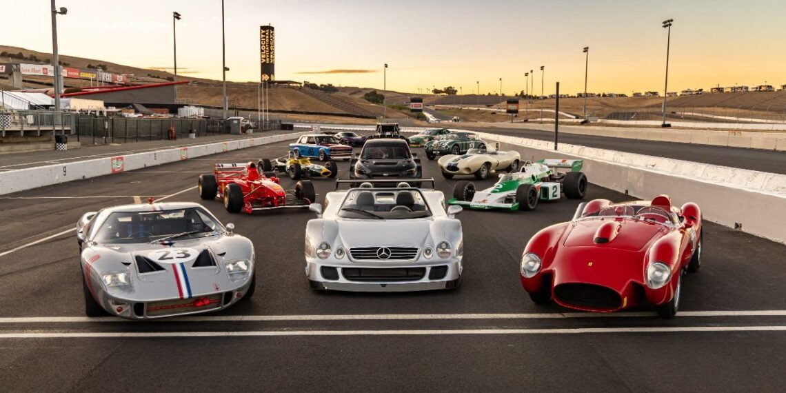 A group of classic and vintage race cars are parked on a race track at sunset, arranged in rows facing the camera, capturing the vibrant spirit of the Sonoma Event at Velocity Invitational.