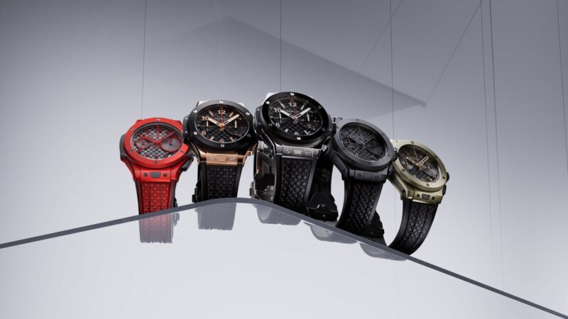 To celebrate their 20th Anniversary, Hublot presents five exquisite Big Bang luxury watches in various colors, elegantly displayed on a slanted transparent surface against a gradient background.
