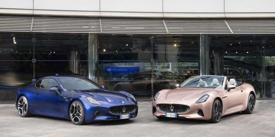 A blue Maserati GranTurismo coupe and a pink convertible sports car are parked side by side in front of a modern glass building in Modena.