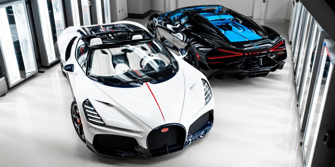 Two luxury sports cars, including a stunning Bugatti W16 Mistral with blue accents, are parked side by side in a well-lit, modern garage after a recent Bugatti delivery from O'Gara Coach.