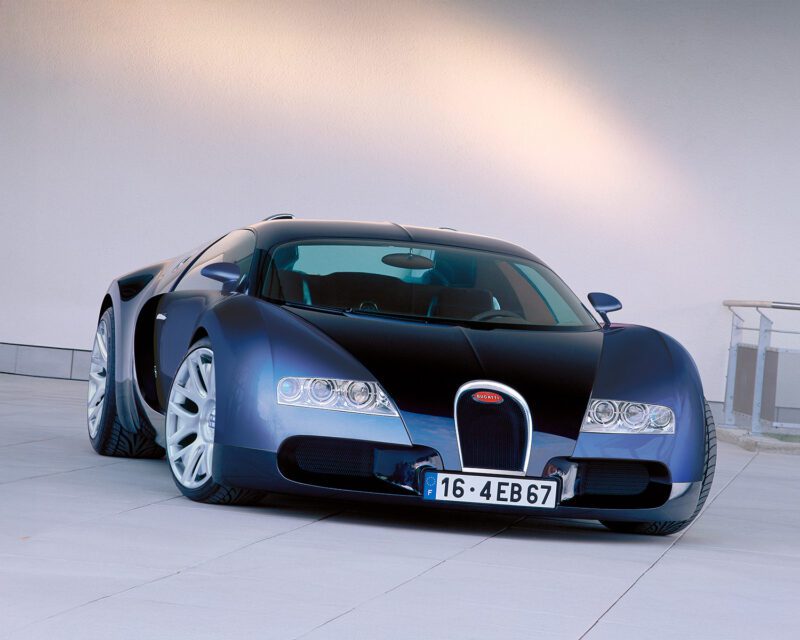 A black and blue luxury sports car is parked on a light-colored tiled surface in front of a plain white wall.