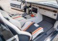Modern car interior featuring white and gray seats with orange accents, a minimalist dashboard, and advanced controls—reminiscent of the bold style found in the iconic 1969 Charger Hellephant—viewed from the passenger side with the door open.