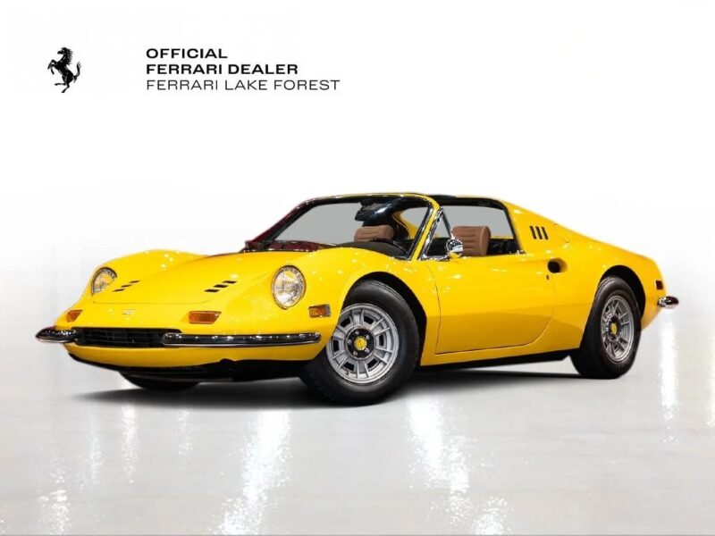 A yellow Ferrari Dino shines in a showroom with a white background and Ferrari Lake Forest dealer branding, perfectly representing the best Ferrari Dino experience.