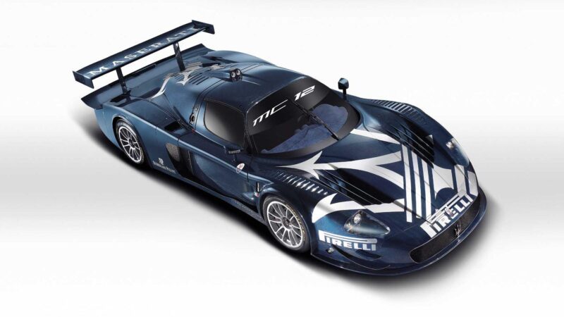 A blue Maserati MC12 race car with white graphics, large rear wing, and Pirelli branding—one of the 10 Enzo Derivates That Only REAL Ferrari Fans Know About—viewed from above against a white background.