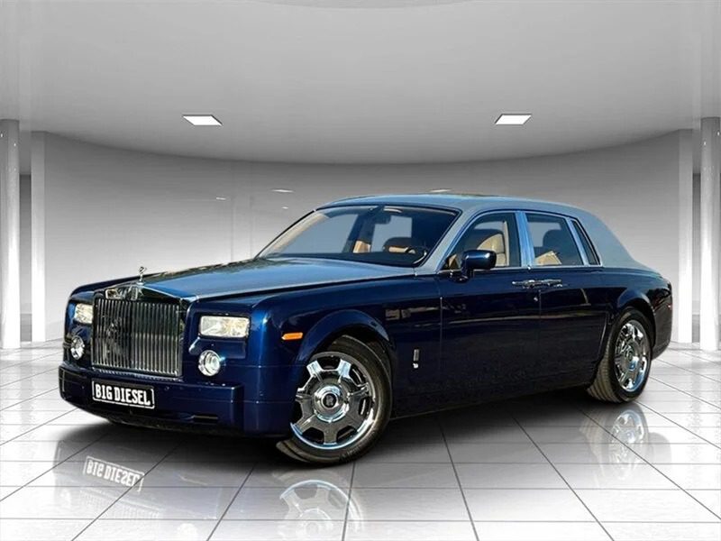 A dark blue Rolls-Royce Phantom sedan, one of the best 2000s cars, is parked indoors on a reflective tiled floor under bright ceiling lights.