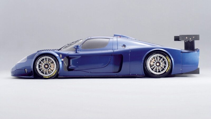 A sleek, blue racing car with aerodynamic design and a large rear wing, reminiscent of the exclusivity found in the 10 Enzo Derivates That Only REAL Ferrari Fans Know About, shown in side profile against a plain, light background.