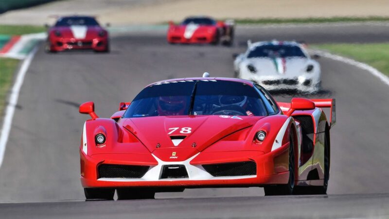A red Ferrari race car with the number 78, inspired by the 10 Enzo Derivates That Only REAL Ferrari Fans Know About, leads other sports cars on a race track during a high-speed event.