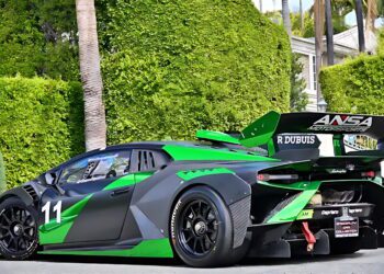 A green and black race car with number 11 and a large rear wing is parked on a street in front of manicured bushes and palm trees—an eye-catching contender among the best supercars under $200k.
