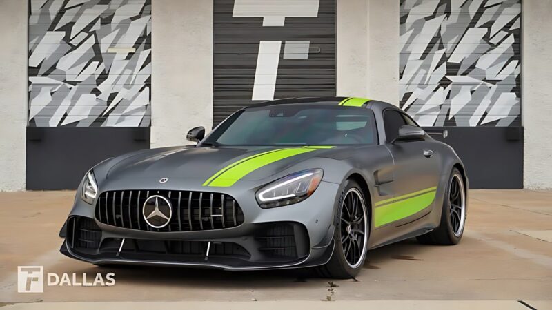 A matte gray Mercedes-AMG GT sports car with neon green racing stripes is parked in front of a garage with geometric-patterned doors. For Sale: Best Supercars Under $200k.