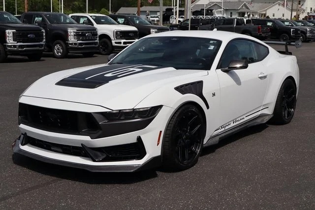 A white Ford Mustang sports car with black racing accents is parked in a dealership lot, standing out among top car listings for anyone seeking an exotic car for sale.