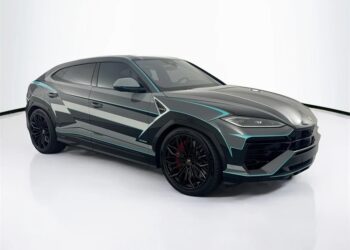 A Lamborghini Urus with a custom grey, black, and teal geometric wrap, black wheels, and red brake calipers stands out in a white studio—an exceptional choice among the best Lamborghini SUVs for sale.