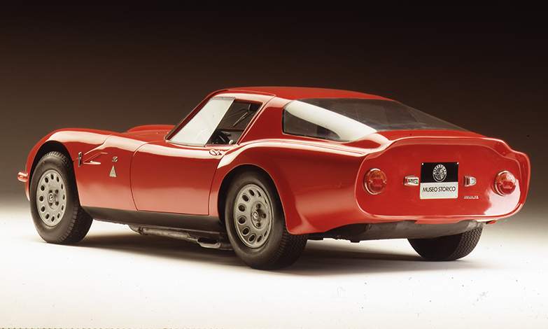 A classic red sports car displayed in a studio setting, viewed from the rear three-quarter angle with a "Museo Storico" license plate, embodies the significance of the 1-of-1 Alfa Romeo DoppiaCoda by Zagato.