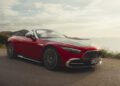 A red 2026 Mercedes-Maybach SL 680 convertible with the top down is parked near the coast, hills and sea in the background, under a partly cloudy sky—soon to be available at US dealers.