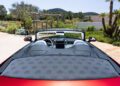 A red 2026 Mercedes-Maybach SL 680 convertible with the top down is parked outdoors near greenery, viewed from the rear seat area on a sunny day.