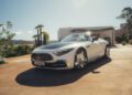 A silver 2026 Mercedes-Maybach SL 680 convertible is parked on a driveway in front of a modern house on a sunny day, awaiting its debut at US dealers.