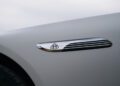 Close-up of a chrome Maybach logo and trim detail on the side of a matte white 2025 Mercedes-Maybach SL 680, soon available at US dealers.