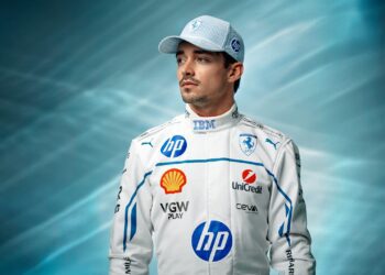 A racing driver in a white and blue Ferrari racing suit and PUMA hat stands against a blue gradient background, looking off to the side, evoking the cool confidence of Charles Leclerc at the Monaco Grand Prix.