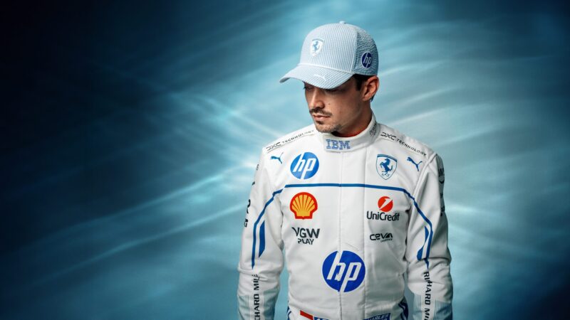 A race car driver in a white and blue Ferrari racing suit and PUMA hat stands against a blue gradient background, looking down—reminiscent of Charles Leclerc at the Monaco Grand Prix.