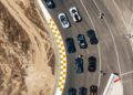 Aerial view of Bugatti sports cars lined up on a racetrack near a curve in Portugal, with visible track markings and several people standing nearby during the Grand Tour 2025.