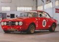 A red vintage Alfa Romeo race car with the number 46 on the door is parked indoors on a concrete floor in a garage, part of the RM Sotheby’s Quadrifoglio Collection Monterey 2025.