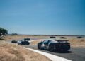 A group of high-end sports cars, including a stunning Bugatti, speeds along a winding racetrack in Portugal under a clear blue sky—an unforgettable scene from the Grand Tour 2025.