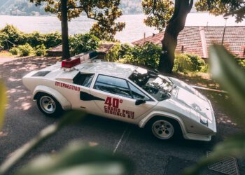 White Lamborghini Countach classic with "40e Grand Prix Monaco 82" and "Intervention" markings, parked outdoors near trees and a body of water, featuring a rooftop light bar—a true icon among race cars.