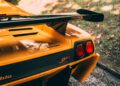 Close-up of the rear section of a yellow Lamborghini Diablo SVR, showcasing taillights, rear wing, and badge details at FuoriConcorso near Villa d'Este, parked beside grass and gravel.