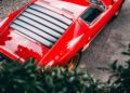 Overhead view of a bright red Lamborghini with black rear window louvers, parked on a paved surface near green foliage, capturing the elegance of FuoriConcorso at Villa d'Este.