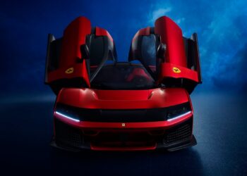 A red Ferrari sports car with both butterfly doors open, viewed from the front against a dark blue background.