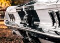 Close-up of the rear end of ECD’s Bespoke '67 Ghost Mustang Fastback, showcasing its emblem, tail lights, and chrome details—now powered by modern muscle from Roush Performance against a blurred outdoor background.