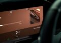 Close-up of a car’s digital dashboard display featuring navigation, media playback, speed at 0 mph, sport mode, and mileage of 1250 miles as Aston Martin becomes the first automaker to debut Apple CarPlay Ultra.