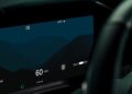 Digital car dashboard displays speed at 60 mph, range of 200 miles, sport mode, time as 12:50 AM, and temperature at 23°C against a dark mountain backdrop—as Aston Martin becomes first automaker to debut Apple CarPlay Ultra.