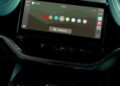 A car infotainment screen displays a color selection menu with various color options, set above climate controls and a central control knob, as Aston Martin becomes the first automaker to debut Apple CarPlay Ultra.