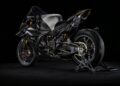A sleek, black Carbon-Clad Concept BMW Motorrad high-performance sport motorcycle is displayed on a paddock stand against a dark background, showcasing the next-generation of RR innovation.