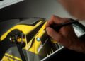 A person uses a stylus to digitally illustrate a yellow, carbon-clad concept BMW Motorrad, showcasing the next generation of RR, on a graphic tablet screen.