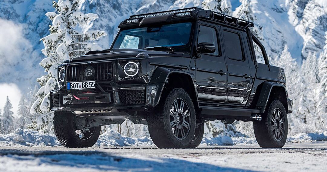 A black BRABUS XLP 800 ADVENTURE pickup truck, based on the Mercedes-AMG G63, is parked on a snowy mountain road with snow-covered trees and mountains in the background.