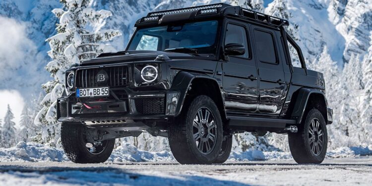 A black BRABUS XLP 800 ADVENTURE pickup truck, based on the Mercedes-AMG G63, is parked on a snowy mountain road with snow-covered trees and mountains in the background.