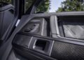 Close-up of a G 63’s interior door panel featuring carbon fiber trim, quilted leather upholstery, seat adjustment controls, and a built-in speaker—showcasing the luxury details of this iconic off-roader.